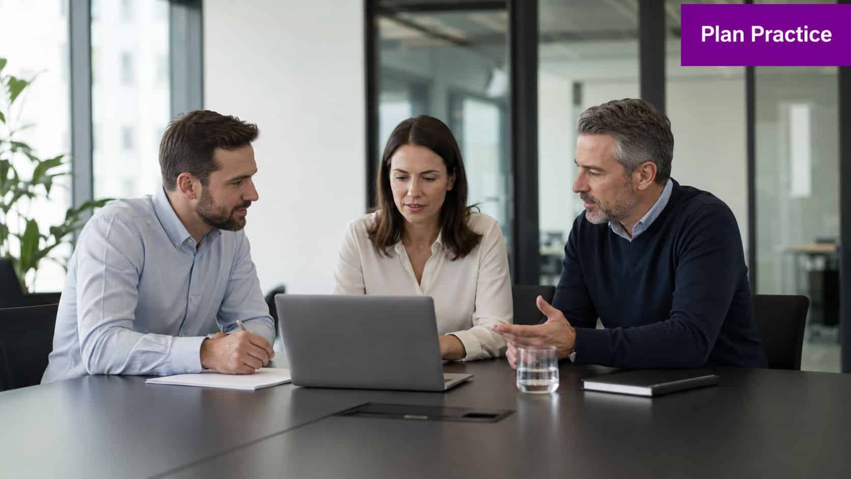A professional team of three people collaborating and discussing a project on a laptop in an office.
